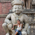 Nepalese boy sitting on Rajput Wrestler, Bhaktapur, Kathmandu.
