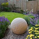 Rainbow sandstone sphere in a town house garden.