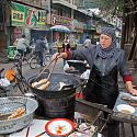 Woman cooking in street, Muslim Quarter, Lanzhou, China.